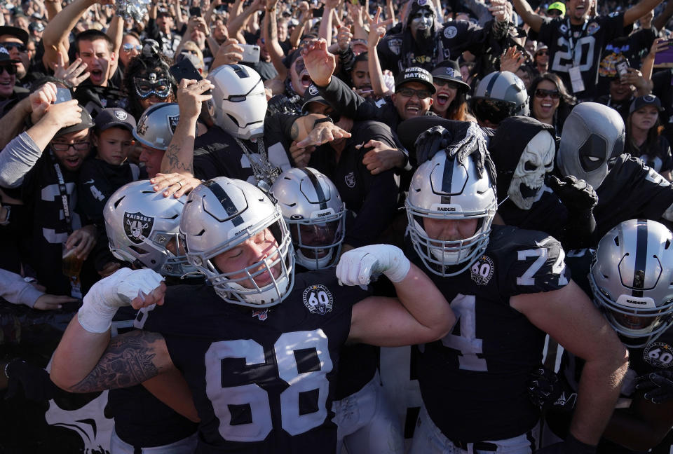 Josh Jacobs (28), Andre James (68), and Kolton Miller (74) of the Oakland Raiders celebrates with fans in the "Black Hole" after Jacobs scored against the Detroit Lions. (Photo by Thearon W. Henderson/Getty Images)