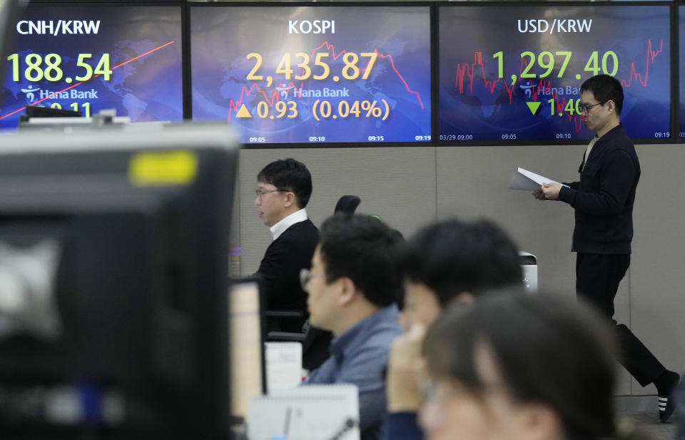 A currency trader passes by the screens showing the Korea Composite Stock Price Index (KOSPI), center, and the foreign exchange rate between U.S. dollar and South Korean won, right, at the foreign exchange dealing room of the KEB Hana Bank headquarters in Seoul, South Korea, Wednesday, March 29, 2023. Asian stocks were mixed Wednesday as anxiety about the global financial system began to fade following three high-profile bank failures.(AP Photo/Ahn Young-joon)