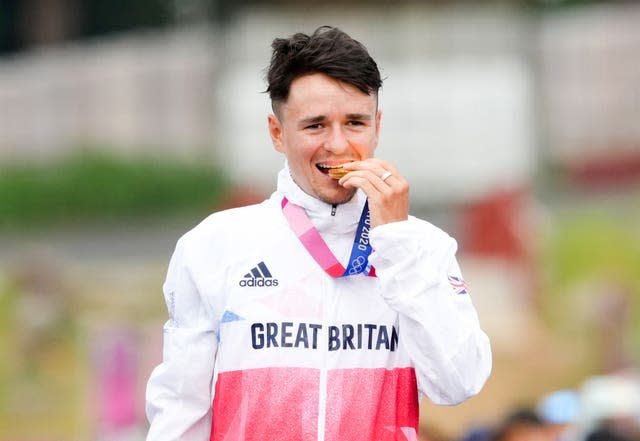 Tom Pidcock bites his gold medal at the presentation ceremony at Tokyo 2020