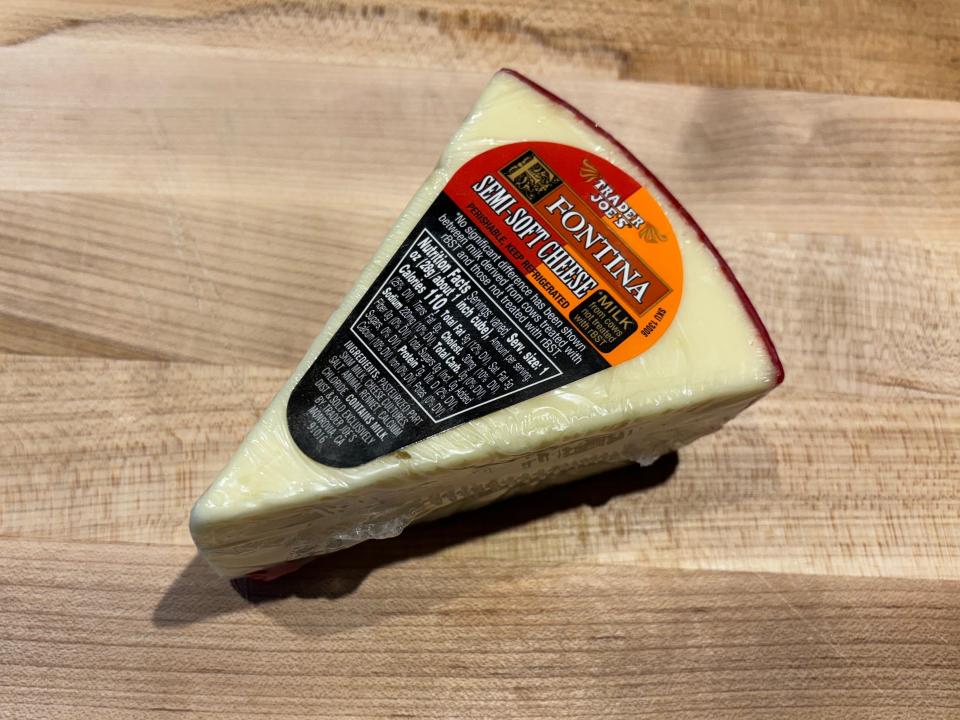 A white wedge of cheese with a red rim and a red and black label reading "Trader Joe's fontina semi-soft cheese"