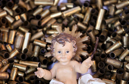 A statue of the baby Jesus on a bed of bullet shells is seen in a Nativity scene outside the Basilica of St Francis in Assisi, Italy, December 21, 2017. The 445 shells represent the number of priests, nuns, monks and religious teachers killed for their faith since 2000. Picture taken December 21, 2017. REUTERS/Alessandro Bianchi