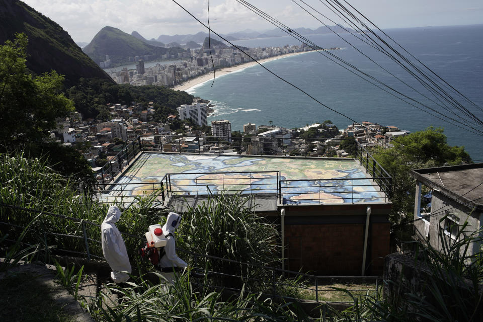 Water utility workers from CEDAE disinfect in the Vidigal favela, which overlooks the oceanfront Leblon and Ipanema neighborhoods, in an effort to curb the spread of the new coronavirus, in Rio de Janeiro, Brazil, Friday, April 24, 2020. (AP Photo/Silvia Izquierdo)