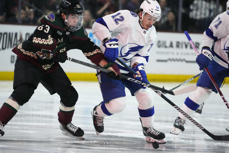 Tampa Bay Lightning center Alex Barre-Boulet (12) battles with Arizona Coyotes left wing Matias Maccelli (63) for the puck during the second period of an NHL hockey game Tuesday, Nov. 28, 2023, in Tempe, Ariz. (AP Photo/Ross D. Franklin)