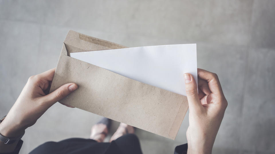 a person pulling a paper out of an envelope