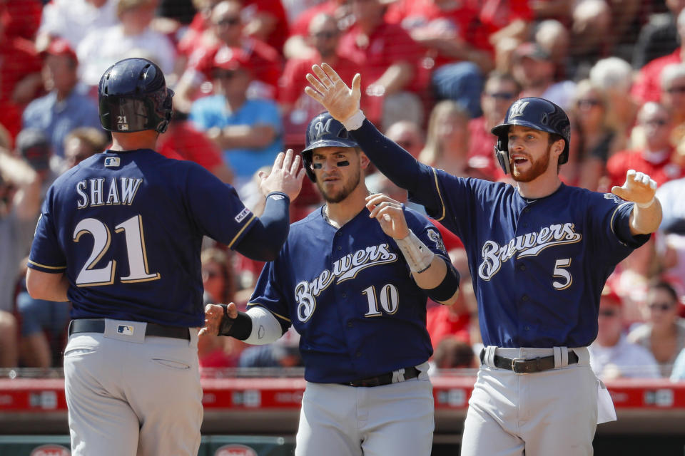From left, Milwaukee Brewers' Travis Shaw, Yasmani Grandal, and Cory Spangenberg celebrate after scoring on a three-run double hit by Orlando Arcia, off Cincinnati Reds starting pitcher Luis Castillo, in the fourth inning of a baseball game, Thursday, Sept. 26, 2019, in Cincinnati. (AP Photo/John Minchillo)