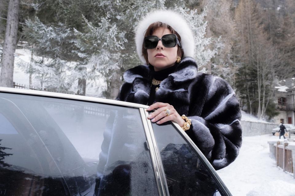 Lady Gaga stands by a car door in furs