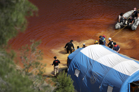 Police forensics officers, rescuers and divers retrieve a suitcase during an investigation for possible bodies of victims of a suspected serial killer in Kokkinopezoula lake, also known as "red lake", near the village of Mitsero, Cyprus, May 5, 2019.REUTERS/Yiannis Kourtoglou