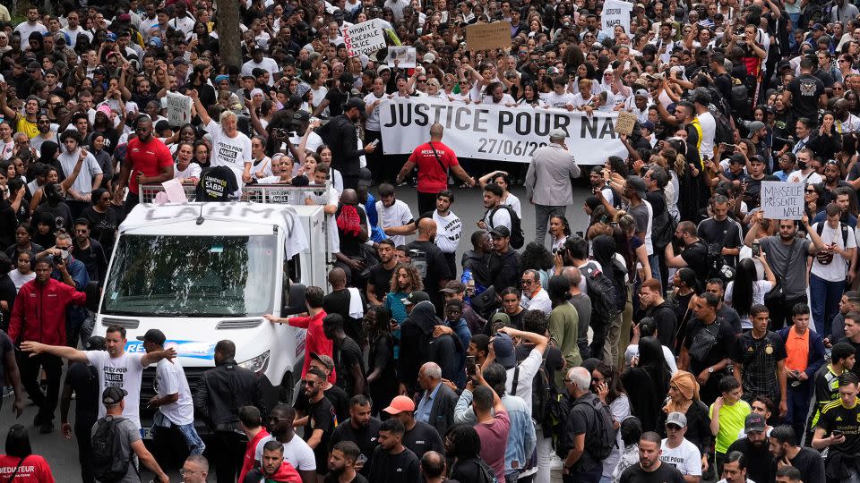 The mother of 17-year-old Nahel, seen at left on a truck, gestures during a march on Thursday. - Michel Euler/AP