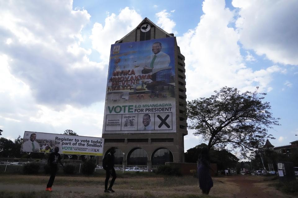 People walk past a portrait of Zimbabwean President Emmerson Mnangagwa at the party headquarters in Harare on June, 8, 2023. Mnangagwa recently announced that national elections will be held on Aug. 23. Allegations of fraud, violence and harassment of opposition members have characterized elections held in Zimbabwe since independence from white minority rule in 1980. (AP Photo/Tsvangirayi Mukwazhi)