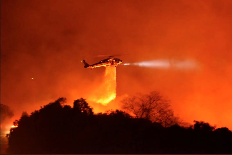 A Los Angeles County Firehawk helicopter makes a water drop on flames during the Cave fire in Los Padres National Forest near East Camino Cielo