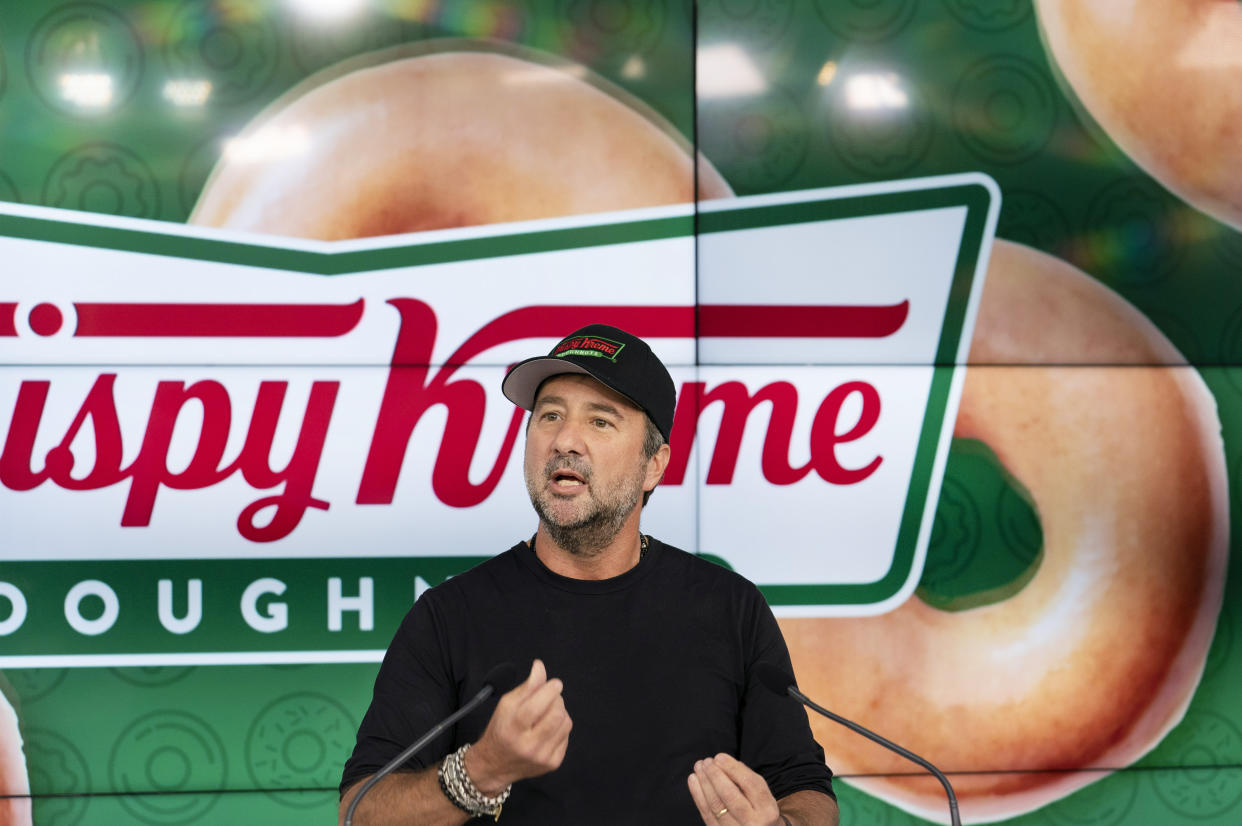 Krispy Kreme CEO Mike Tattersfield speaks in front of a Krispy Kreme doughnut background.