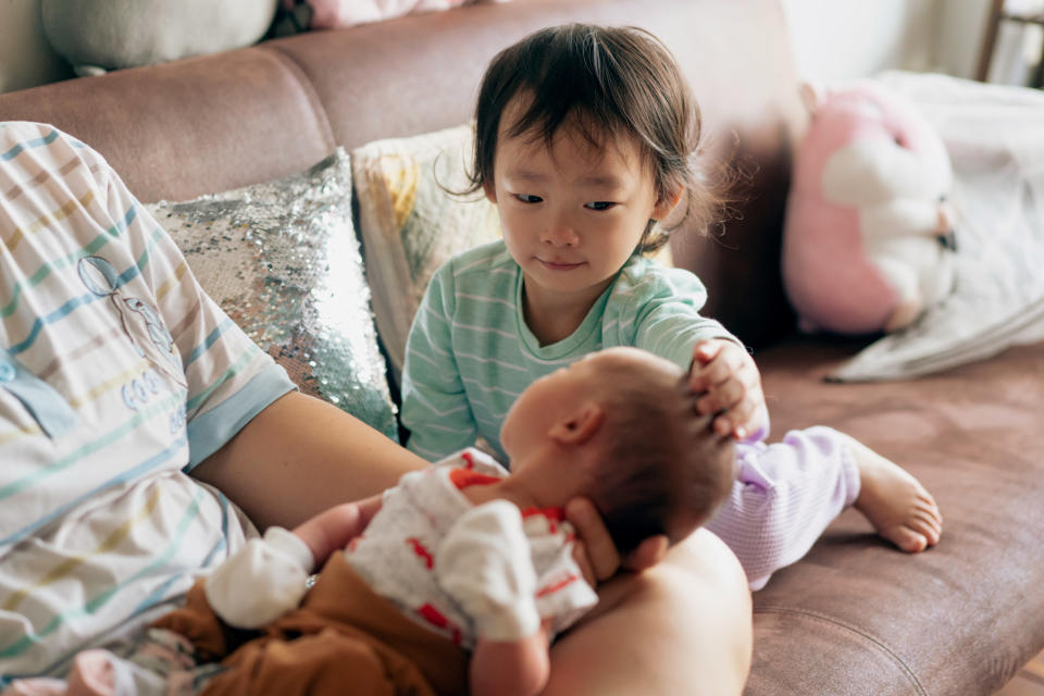 A young girl watches over her baby sister