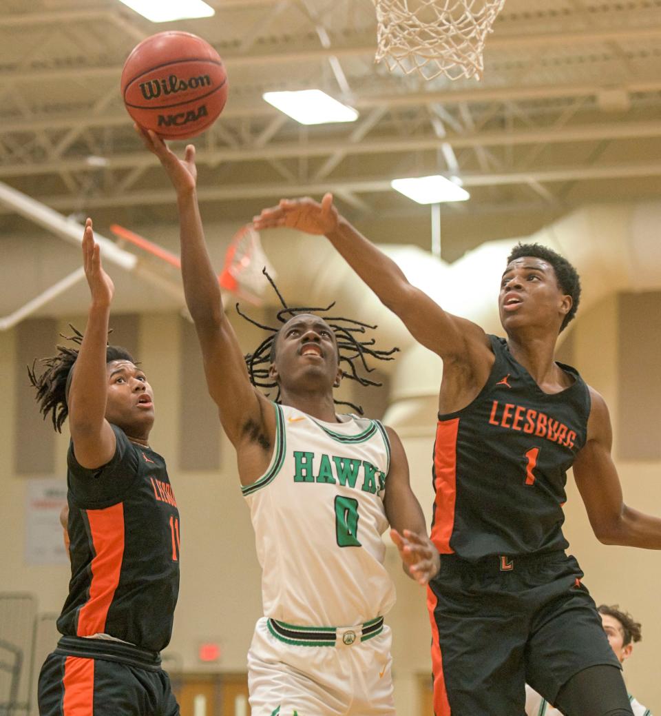 Lake Minneola’s Damien Franklin scores against Leesburg's Kanye Gaines (11) and Jermarien Williams (1) during Tuesday's game in Minneola.