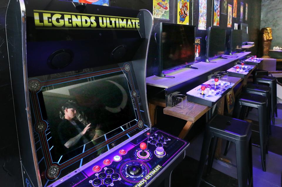 Dave Schweyer, co-owner of Linda Theater, is reflected in the screen of a video game as he talks about he bank of video games  at his adjacent business Cafe Rewind which is in the former post office building on Goodyear Blvd. in Goodyear Heights neighborhood of Akron.