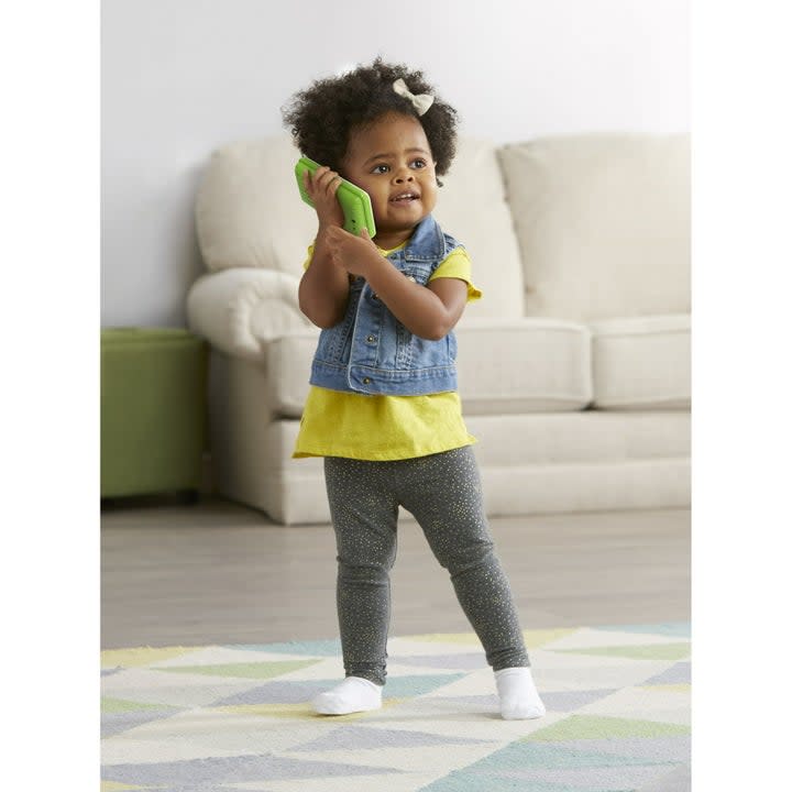 girl pretending to talk on a toy green cell phone