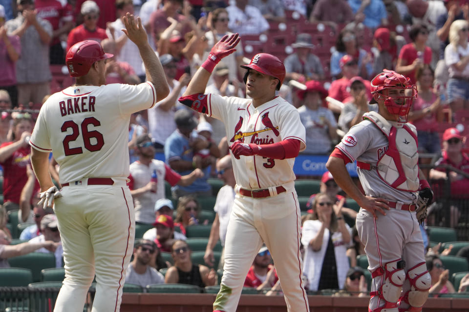 St. Louis Cardinals' Dylan Carlson is congratulated by teammate Luken Baker (26) after hitting a two-run home run as Cincinnati Reds catcher Luke Maile, right, stands by during the eighth inning of a baseball game Saturday, June 10, 2023, in St. Louis. (AP Photo/Jeff Roberson)