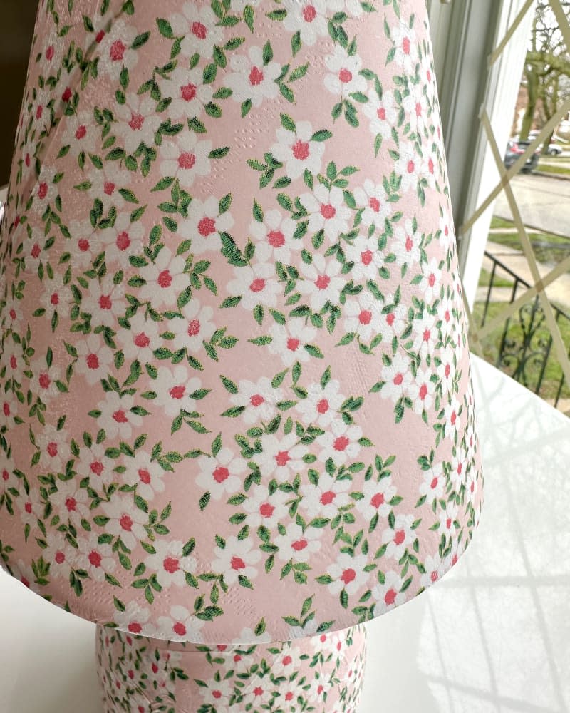 White hand painted flowers painted on pink painted lamp.