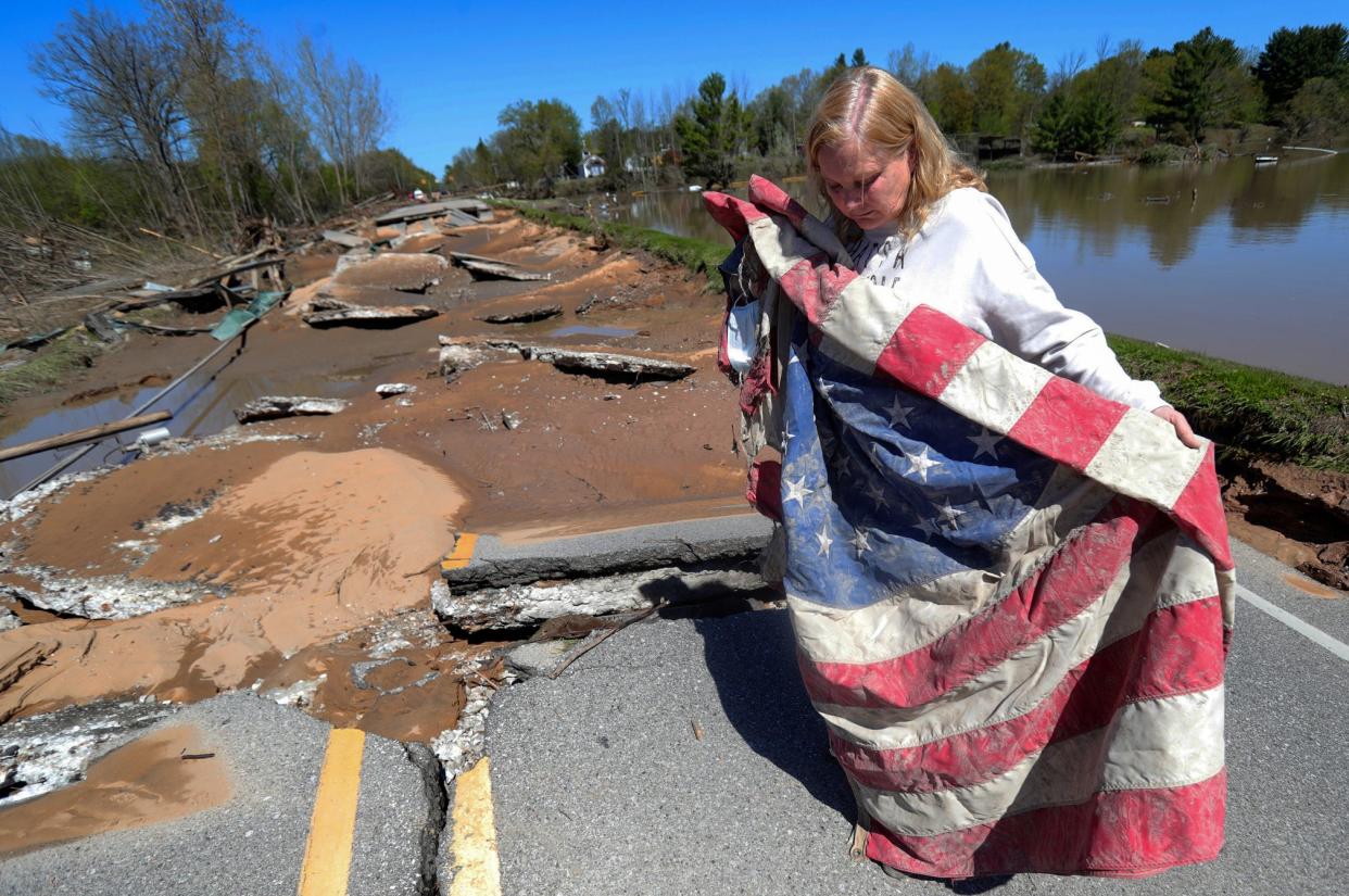 Kim Burgess unfolds a flag she recovered from the Veterans War memorial dedicated veterans and her son lance corporal Ryan Burgess who was killed in Iraq. The Veterans Memorial stood near Saginaw Rd. in Sanford Michigan on May 21, 2020.  The Sanford dam that held the Tittabawassee river failed causing massive flooding destroying homes and businesses.