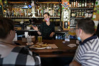 Bartender Alyssa Dooley, center, talks with customers at Mo's Irish Pub, Tuesday, March 2, 2021, in Houston. Texas Gov. Greg Abbott announced that he is lifting business capacity limits and the state's mask mandate starting next week. (AP Photo/David J. Phillip)