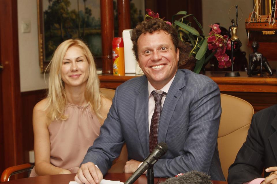 Russian businessman Sergei Polonsky, right, smiles together with his wife Olga, left, during a press conference in Phnom Penh, Cambodia, Friday, April 25, 2014. Cambodia's highest court ruled Friday that a prominent Russian property developer wanted in his homeland for allegedly embezzling millions of dollars cannot be extradited. (AP Photo/Heng Sinith)