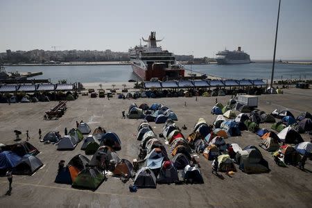 Refugees and migrants make their way next to tents at a makeshift camp at the port of Piraeus, near Athens, Greece April 6, 2016. REUTERS/Alkis Konstantinidis