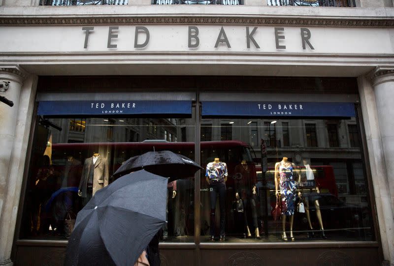 FILE PHOTO: People shelter under umbrellas as they pass a Ted Baker a store in London, Britain