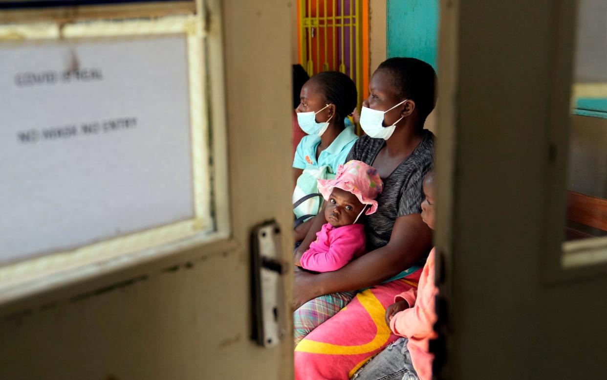 Women holding their babies wait for a measles vaccine in Harare, after being told "to just sneak out" to save their children from measles, despite the disapproval of religious groups - AP Photo/Tsvangirayi Mukwazhi