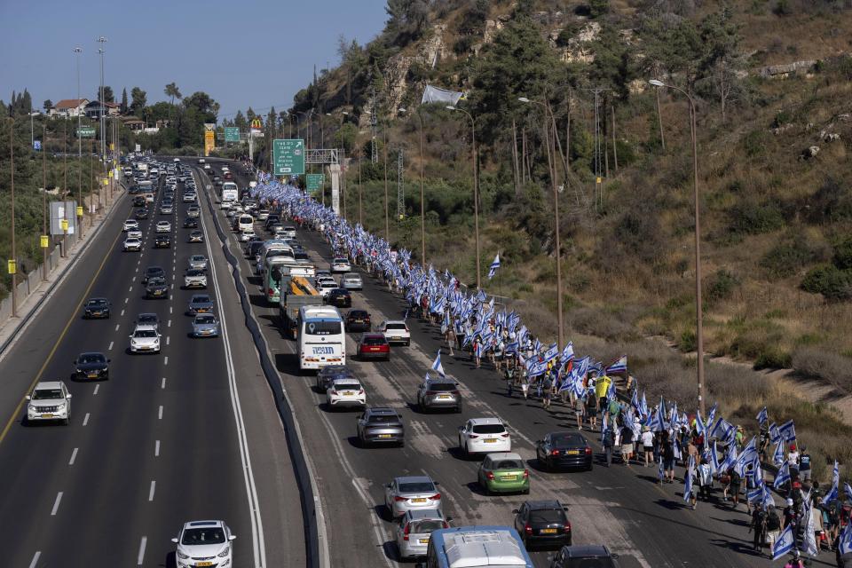 Israelis march along Highway 1 on their way to Jerusalem near Moshav Shoresh in Israel, as part of protests against plans by Prime Minister Benjamin Netanyahu's government to overhaul the judicial system, Friday, July 21, 2023. The protest march from Tel Aviv to Jerusalem is growing as Netanyahu vows to forge ahead on the controversial overhaul. Protest organizers planned to camp overnight at Shoresh, before making their way to Israel's parliament on Saturday. (AP Photo/Ohad Zwigenberg)