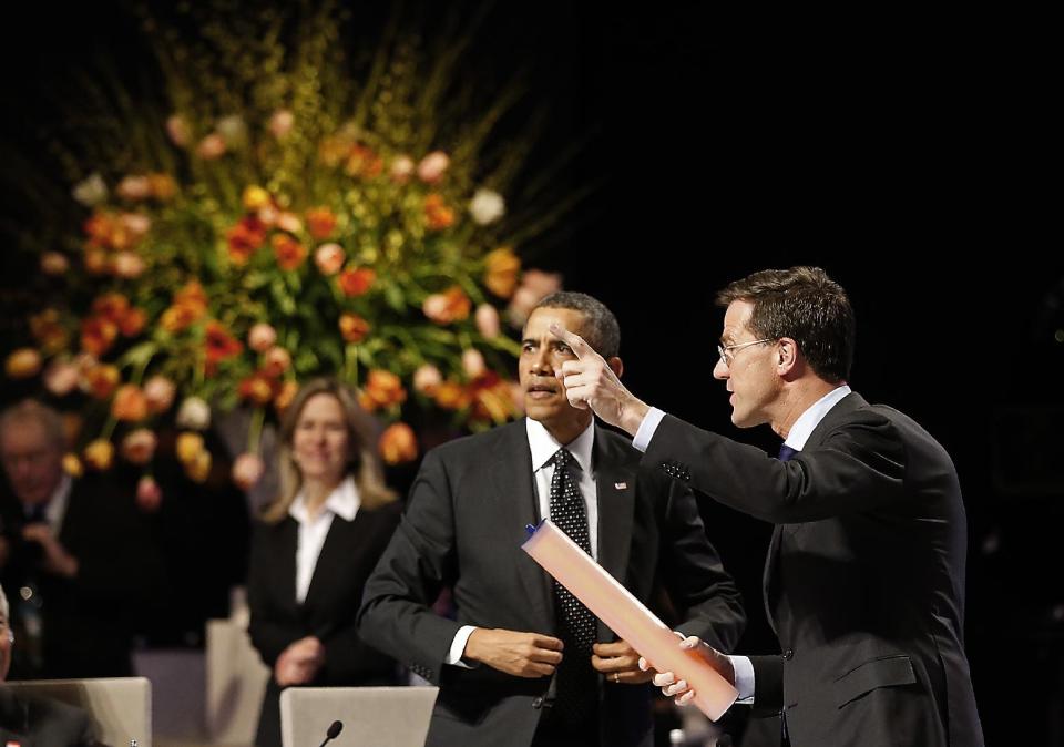 Dutch Prime Minister Mark Rutte, right, points towards a symbolic stick as he hands over the chair to U.S. President Barack Obama, center, during the closing session on the last day of the Nuclear Summit in The Hague, Netherlands, Tuesday, March 25, 2014. Thirty-five countries pledged Tuesday to turn international guidelines on nuclear security into national laws, a move aimed at preventing terrorists from getting their hands on nuclear material. Tuesday's initiative following a two-day summit of leaders also commits countries to open up their security procedures to independent review, a further step toward creating an international legal framework to thwart nuclear terrorism, said a joint statement from the Netherlands, the United States and South Korea. (AP Photo/Frank Augstein, POOL)