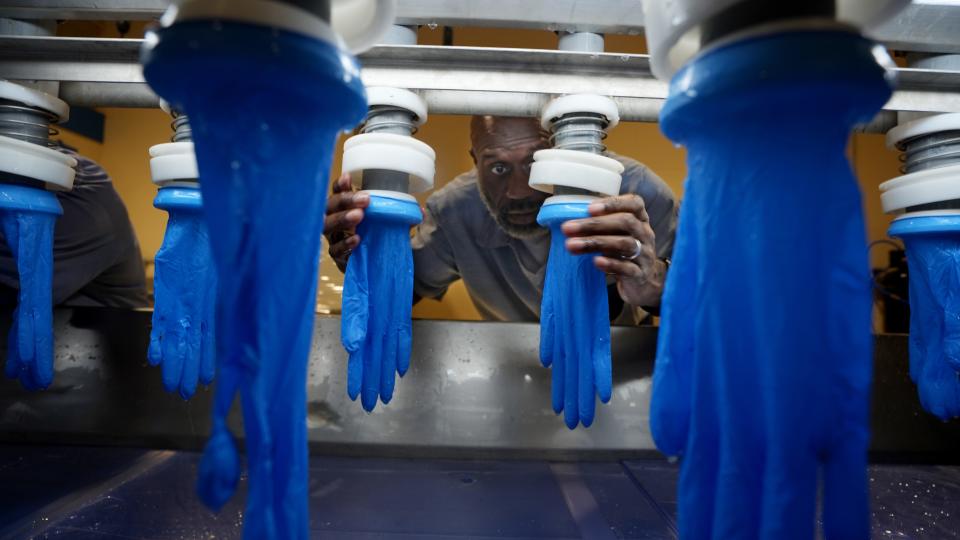 Inmate Lloyd Black sets sample gloves on a tensile-testing machine inside the Madison Correctional Institution in London. Summit Glove, a Minerva, Ohio-based company, is a consultant at the prison where they are building a factory to produce gloves. The prison uses Summit's intellectual property and formulas to manufacture gloves that will be used by corrections officers and prison staff.