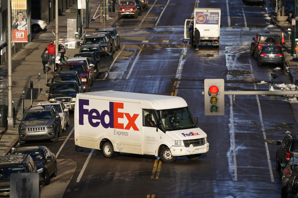 FILE - In this Tuesday, Dec. 29, 2020, file photo, a FedEx delivery vehicle makes a U-turn near the Denver Pavilions, in downtown Denver. FedEx says its profit nearly tripled in its most recent quarter, despite winter weather that hobbled some of its facilities. Online shopping has surged during the pandemic as more people avoid going inside stores. (AP Photo/David Zalubowski, File)