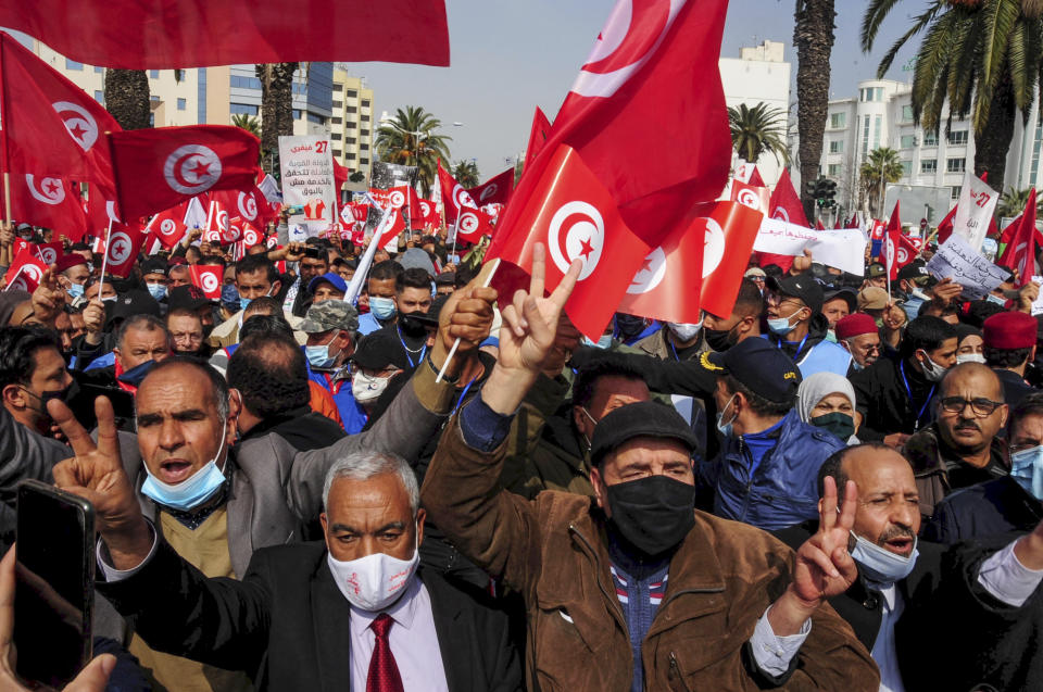 Supporters of the islamist Ennada party march with Tunisian flags during a rally in Tunis, Tunisia, Saturday, Feb. 27, 2021. The party, Ennahdha, led by House Speaker Rached Ghannouchi, has backed Prime Minister Hichem Mechichi in his standoff with President Kais Saied over a cabinet reshuffle. (AP Photo/Hassene Dridi)