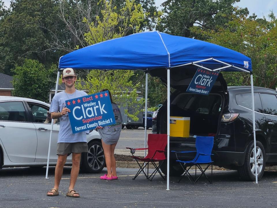 Forrest County District 1 supervisor candidate Wesley Clark supporters hold up signs as motorists pass by outside Hardy Street Baptist Church precinct.