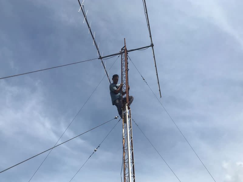 Munandar, radio communication technician, climbs as he checks tower in Banda Aceh
