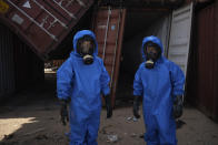 French emergency workers, part of a special unit working with chemicals, stand next to damaged shipping containers at the site of last week's explosion, in the port of Beirut, Lebanon, Monday, Aug. 10, 2020. The unit is identifying potential leaks and securing an area where containers with flammable liquids have been damaged by the blast. (AP Photo/Felipe Dana)