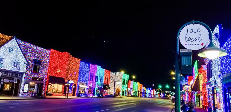 downtown buildings covered in different colored lights,with a sign that reads love local rochester