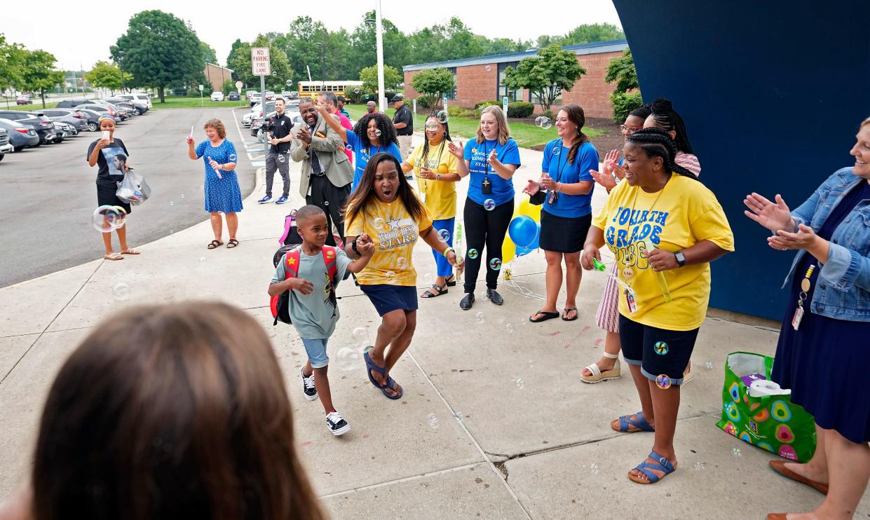 Woodcrest Elementary student Ayden Bailey, 6, walks into school with instructional coach Jeri Hensley on the first day back to school on July 27. Woodcrest Elementary is the only Columbus City Schools year-round school.