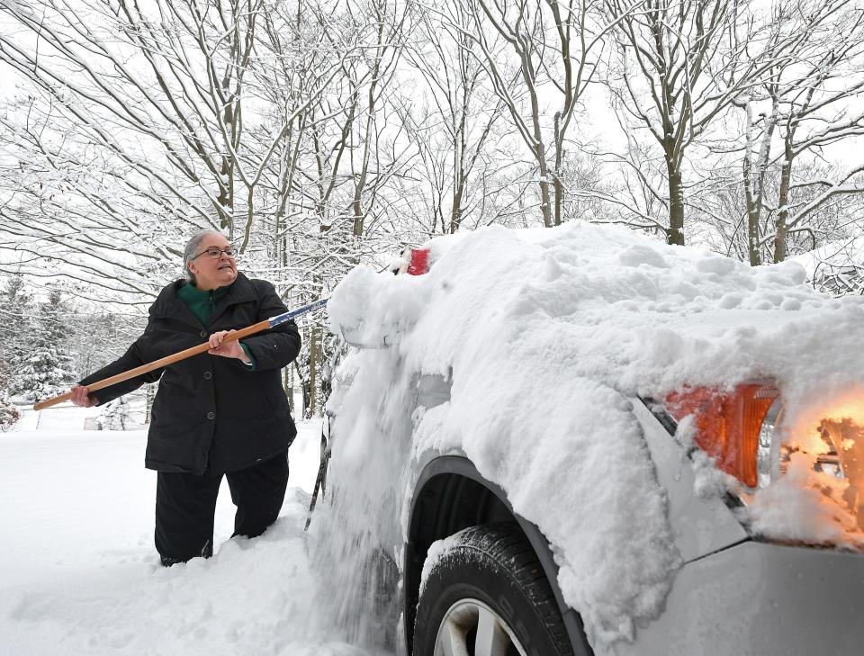 Sally Jones brushes snow off her car at her home Monday in the 4300 block of Steger Road in Greene Township. There appeared to be about 6 inches of lake-effect snow that fell in the Wattsburg area on Sunday, but "it looked like a foot of snow on the roof of the car," said Jones, 63, who was on her way to work Monday morning.