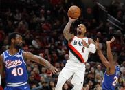 Portland Trail Blazers guard Damian Lillard, center, shoots as Sacramento Kings forward Harrison Barnes, left, and forward Harry Giles III, right, defend during the first half of an NBA basketball game in Portland, Ore., Saturday, March 7, 2020. (AP Photo/Steve Dipaola)