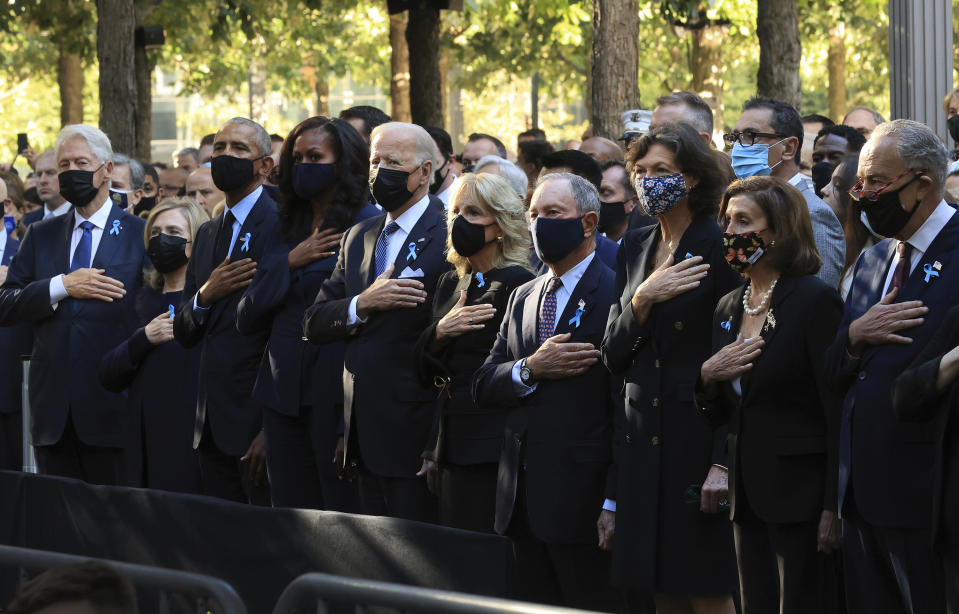 CORRECTS TITLE TO SENATE MAJORITY LEADER - From left, former President Bill Clinton, former First Lady Hillary Clinton, former President Barack Obama, Michelle Obama, President Joe Biden, first lady Jill Biden, former New York City Mayor Michael Bloomberg, Bloomberg's partner Diana Taylor, Speaker of the House Nancy Pelosi, D-Calif., and Senate Majority Leader Charles Schumer, D-N.Y., stand for the national anthem during the annual 9/11 Commemoration Ceremony at the National 9/11 Memorial and Museum on Saturday, Sept. 11, 2021 in New York. (Chip Somodevilla/Pool Photo via AP)