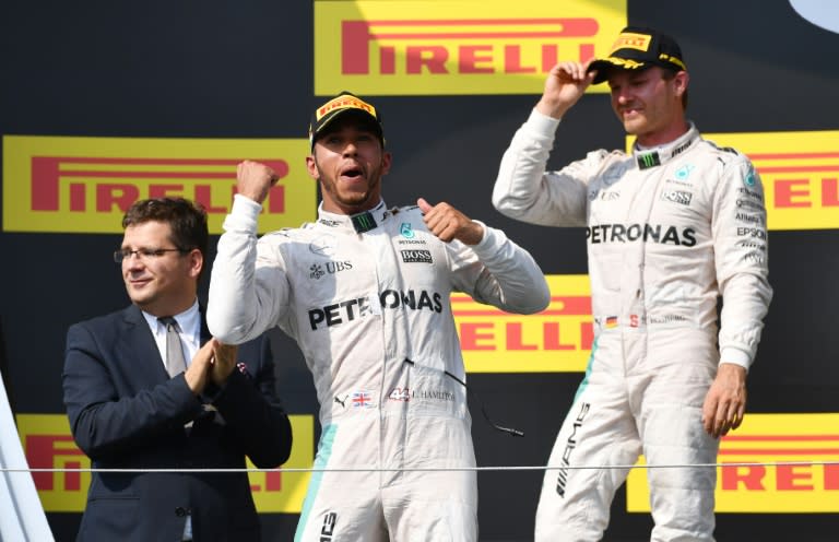 Mercedes AMG Petronas F1 Team's British driver Lewis Hamilton (L) celebrates in front of his German teammate driver Nico Rosberg (R) in Budapest on July 24, 2016