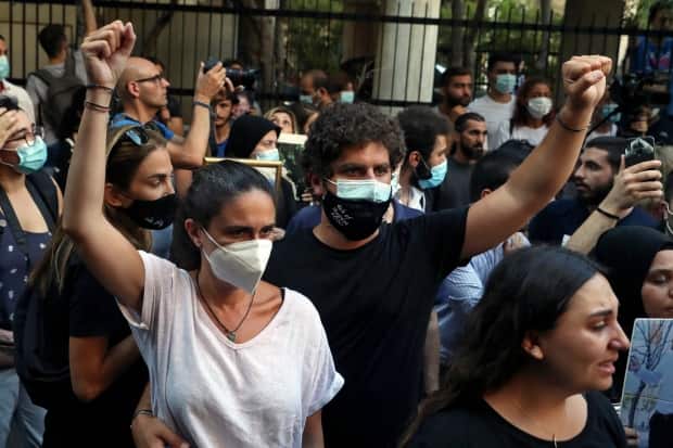 Tracy and Paul Naggear raise their fists during a protest outside the home of caretaker Interior Minister Mohamed Fehmi in Beirut on July 13, 2021. (Bilal Hussein/The Associated Press - image credit)