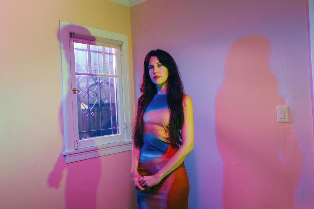 A portrait of a woman with dark hair and colorful dress.