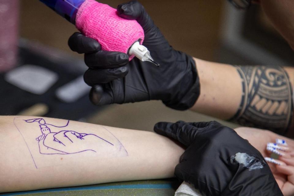 Tattoo artist Bella Harrell works on client Savannah Smith at Khaotic Zen Tattoo in Fort Worth on Thursday, March 23, 2023.