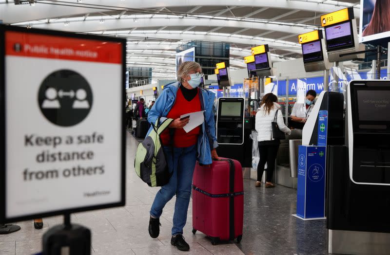 A passenger walks with her luggage at the Terminal 5 departures area at Heathrow Airport in London