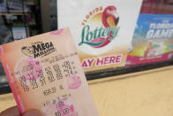 A customer shows off a Mega Millions lottery ticket after purchasing it, Wednesday, Jan. 13, 2021, in Orlando, Fla. Lottery players will have a shot Friday night at the fifth-largest jackpot in U.S. history after no tickets matched all the numbers in the latest Mega Millions drawing. (AP Photo/John Raoux)