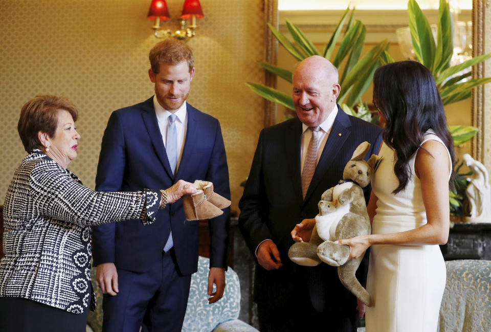 Britain's Prince Harry and Meghan, Duchess of Sussex react as they receive gifts from by Australia's Governor General Sir Peter Cosgrove and his wife Lady Cosgrove at Admiralty House in Sydney, Australia, Tuesday, Oct. 16, 2018. Prince Harry and his wife Meghan are on a 16-day tour of Australia and the South Pacific.(Phil Noble/Pool via AP)