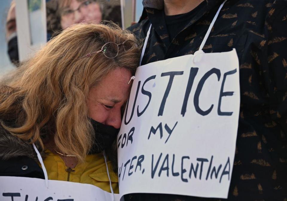 A mother buries her head in her husband's chest as she cries during a news conference.