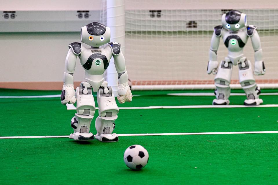 A Texas Robotics RoboCup soccer team robot chases the ball at an indoor soccer field in the Anna Hiss Gymnasium.