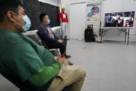 Workers Justice Project Director Gonzalo Cruz, left, and organizer Juan Carlos Romero watch President Joe Biden's presidential inauguration on TV from the Workers Justice Center, Wednesday, Jan. 20, 2021, in the Sunset Park neighborhood of Brooklyn in New York. The Workers Justice Project is a Brooklyn based non-profit that helps immigrants. (AP Photo/Kathy Willens)